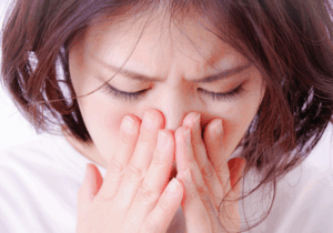 鼻と口を押える女性