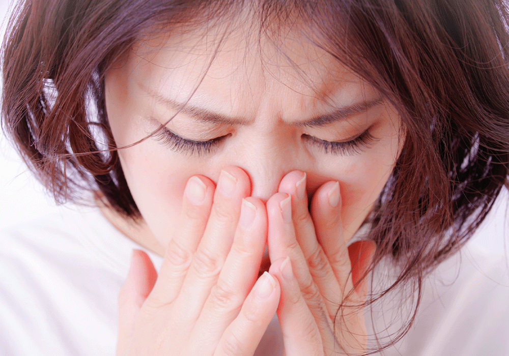 鼻と口を押える女性